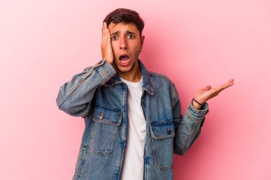 Sarı arka planda izole edilmiş dövmeleri olan beyaz genç bir adam, avuç içi fotokopi alanını elinde tutmaktan etkilenmiş..