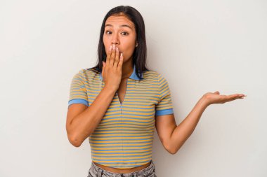 Beyaz arka planda izole edilmiş genç Latin kadın, avuç içinde kopya alanı tutmaktan etkilenmiş..