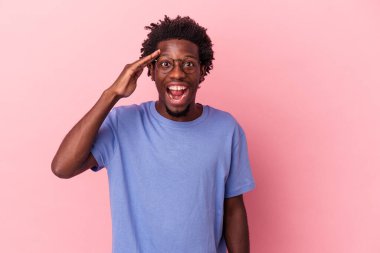 Pembe arka planda izole edilmiş genç bir Afrikalı Amerikalı yüksek sesle bağırıyor, gözleri açık ve elleri gergin tutuyor..