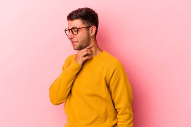 Sarı arka planda dövmeleri olan beyaz genç bir adam virüs ya da enfeksiyon yüzünden boğazında ağrı hissediyor..