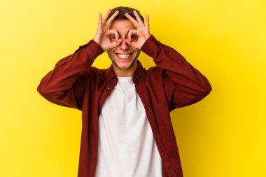 Sarı arka planda izole edilmiş beyaz dövmeli genç bir adam heyecanlı..