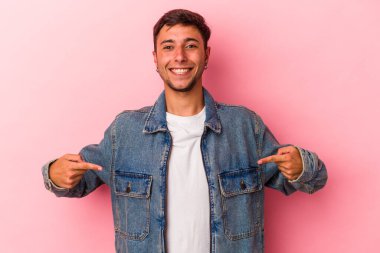 Sarı arka planda izole edilmiş dövmeleri olan beyaz bir genç. Parmakları aşağıda, olumlu hisler içinde..