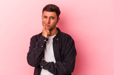 Sarı arka planda izole edilmiş beyaz dövmeli genç adam alaycı bir ifadeyle kameraya bakıyor..