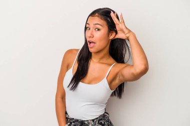 Beyaz arka planda izole edilmiş genç Latin bir kadın bir dedikoduyu dinlemeye çalışıyor..