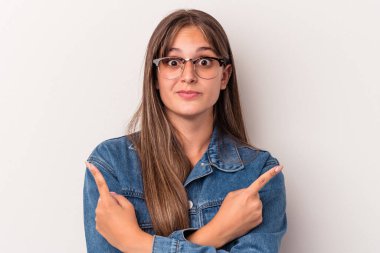 Beyaz arka plan noktalarında izole genç beyaz kadın, iki seçenek arasında seçim yapmaya çalışıyor.