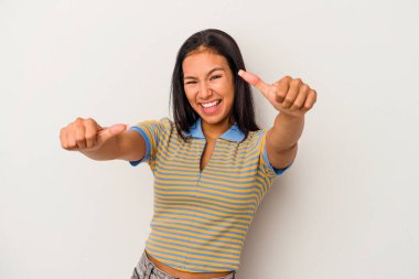 Beyaz arka planda izole edilmiş genç Latin bir kadın. Baş parmağını kaldırıyor, gülümsüyor ve kendinden emin..