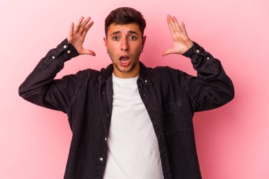 Sarı arka planda izole edilmiş dövmeleri olan genç beyaz bir adam zaferi ya da başarıyı kutluyor, şaşırıyor ve şok oluyor..