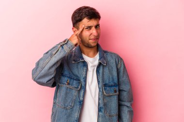 Sarı arka planda izole edilmiş beyaz dövmeli genç bir adam şakağı parmağıyla işaret ediyor, düşünüyor ve bir göreve odaklanıyor..