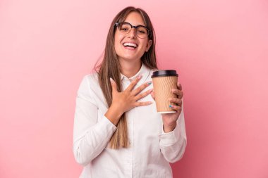 Kafkasyalı genç bir kadın pembe arka planda izole edilmiş bir şekilde elini göğsüne koyup kahkahalar atıyor..