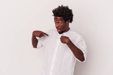 Beyaz arka planda izole edilmiş genç bir Afro-Amerikan erkeği parmağını gösterip gülümseyerek şaşırdı..