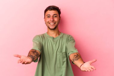 Sarı arka planda dövmeleri olan beyaz bir genç hoş bir yüz ifadesi sergiliyor..