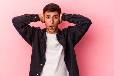 Sarı arka planda izole edilmiş dövmeleri olan genç beyaz bir adam kulaklarını elleriyle kapatıyor ve çok fazla ses duymamaya çalışıyor..