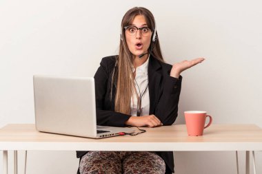 Beyaz arka planda izole bir şekilde seyahat eden beyaz tenli genç bir kadın, avuç içi fotokopi alanını elinde tutmaktan etkilenmiş..