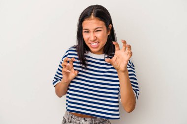 Beyaz arka planda izole edilmiş genç Latin kadın pençelerini kedi taklidi yaparken gösteriyor, agresif bir hareket..