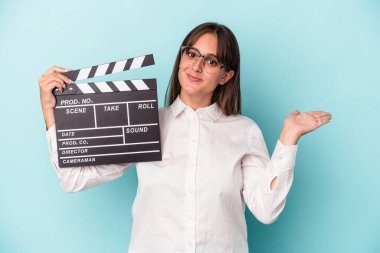 Mavi arka planda el çırpma tahtası tutan beyaz bir kadın bir avuç içinin fotokopi çektiğini ve belinde bir el daha tuttuğunu gösteriyor..