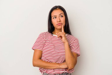 Beyaz arka planda izole edilmiş genç Latin kadın şüpheli ve şüpheci bir ifadeyle yana bakıyor..