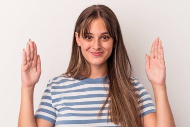 Beyaz arka planda izole edilmiş genç beyaz bir kadın. Elinde parmakları olan, gülümseyen ve kendinden emin bir şey tutuyor..