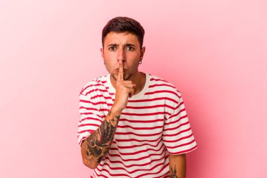 Sarı arka planda izole edilmiş dövmeleri olan genç beyaz bir adam ya sır saklıyor ya da sessizlik istiyor..