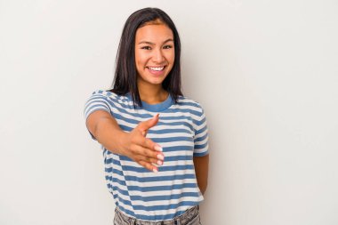 Beyaz arka planda izole edilmiş genç Latin bir kadın selamlama jesti olarak kameraya elini uzatıyor..