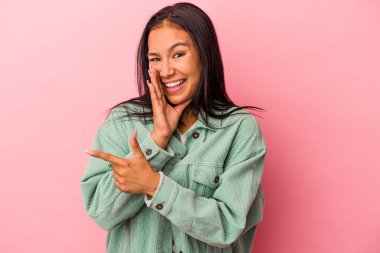 Genç Latin bir kadın pembe arka planda izole edilmiş. Dedikodu yapıyor, bir şeyleri bildiriyor..