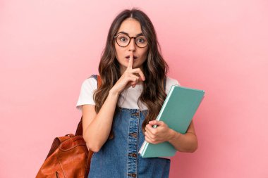 Young caucasian student woman isolated on pink background keeping a secret or asking for silence.