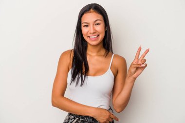 Beyaz arka planda izole edilmiş genç Latin kadın zafer işareti gösteriyor ve gülümsüyor..