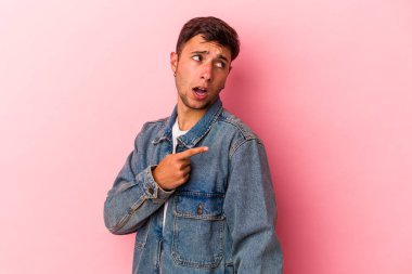 Sarı arka planda dövmeleri olan genç beyaz bir adam. Baş parmak uzakta, gülüyor ve kaygısız..