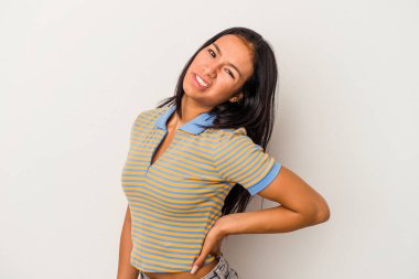 Beyaz arka planda sırtı ağrıyan genç Latin bir kadın..