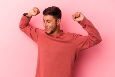 Sarı arka planda, özel bir günü kutlayan dövmeli, genç, beyaz bir adam atlıyor ve enerjiyle kollarını kaldırıyor..