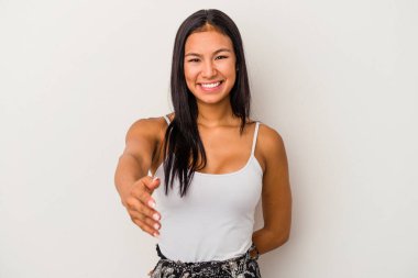 Beyaz arka planda izole edilmiş genç Latin bir kadın selamlama jesti olarak kameraya elini uzatıyor..