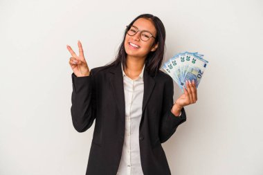 Elinde banknotlar tutan genç Latin kadın beyaz arka planda izole edilmiş kahve iki numarayı parmaklarıyla gösteriyor..