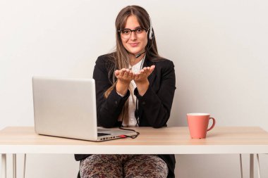 Beyaz arka planda seyahat eden beyaz tenli genç bir kadın elinde avuç içi bir şeyle kameraya sunuyor..