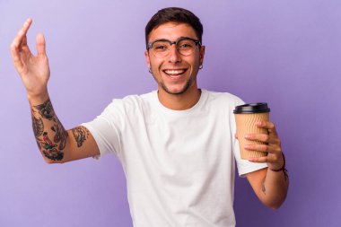 Elinde mor arka planda izole edilmiş kahve taşıyan genç beyaz adam hoş bir sürpriz alıyor, heyecanlı ve el kaldırıyor..