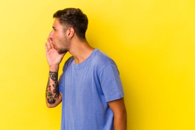 Sarı arka planda izole edilmiş dövmeleri olan beyaz genç bir adam gizli bir fren haberinin olduğunu söylüyor.