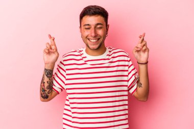 Sarı arka planda, şans dilemek için izole edilmiş dövmeleri olan genç beyaz bir adam.