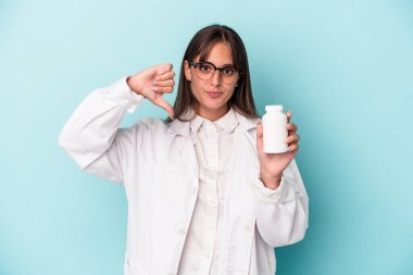 Mavi arka planda hapları tutan genç bir eczacı kadın hoşlanmadığı bir jestte bulundu. Anlaşmazlık konsepti.