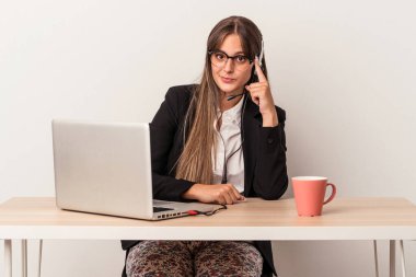 Beyaz arka planda izole bir şekilde seyahat eden beyaz tenli genç bir kadın tapınağı parmağıyla işaret ediyor, düşünüyor ve bir göreve odaklanıyor..