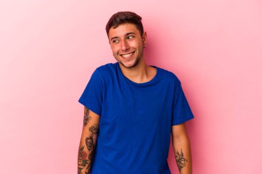 Sarı arka planda izole edilmiş dövmeleri olan genç beyaz adam gülüyor ve gözlerini kapıyor, rahatlamış ve mutlu hissediyor..