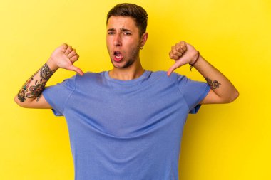 Sarı arka planda izole edilmiş dövmeleri olan beyaz bir genç gururlu ve kendinden emin..