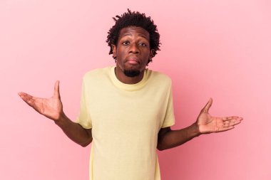 Genç Afrikalı Amerikalı, pembe arka planda izole edilmiş. Sorgulama sırasında omuz silkiyor ve şüphe ediyor..