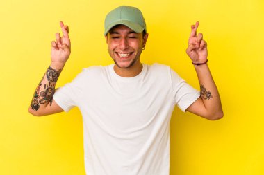 Sarı arka planda, şans dilemek için izole edilmiş dövmeleri olan genç beyaz bir adam.