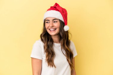 Sarı arka planda izole edilmiş bir şekilde Noel 'i kutlayan beyaz bir kadın gülümsüyor, neşeli ve keyifli görünüyor..