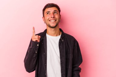 Sarı arka planda dövmeleri olan beyaz genç bir adam iki ön parmağı da boş bir alan gösteriyor..