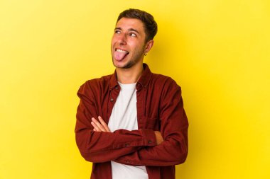 Sarı arka planda izole edilmiş beyaz dövmeli genç bir adam. Komik ve dost canlısı bir dil uzatıyor..