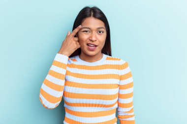 Genç Venezuelalı bir kadın mavi arka planda izole edilmiş işaret parmağıyla hayal kırıklığı jesti yapıyor..