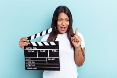 Genç Venezuelalı bir kadın mavi arka planda izole edilmiş bir alçıpan tutuyor. Bir fikri var, ilham verici bir kavram..