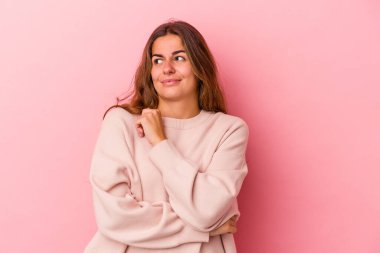 Pembe arka planda izole edilmiş genç beyaz kadın kafası karışmış, kuşkulu ve güvensiz hissediyor..