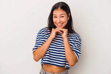 Beyaz arka planda izole edilmiş genç Latin bir kadın şans için dua ediyor, şaşırmış ve ağzını açıp önüne bakıyor..