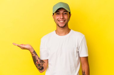 Sarı arka planda dövmeleri olan genç beyaz bir adam avuçta fotokopi alanı ve belinde bir el daha olduğunu gösteriyor..