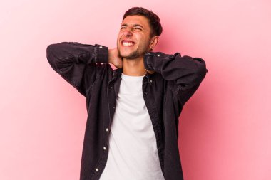 Sarı arka planda izole edilmiş beyaz dövmeli genç bir adam sabit yaşam tarzından dolayı boyun ağrısı çekiyor..